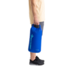 De perfil, una persona sostiene una bolsa impermeable ligera Bolsa Sea To Summit. Vestida con una camisa ligera, pantalones cortos grises y zapatillas negras, está lista para la aventura, con el logotipo familiar visible en la bolsa.