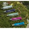 Cinco navajas de bolsillo Cuchillo Opinel N°6 Trekking, con mangos en tonos beige, violeta, verde, rosa y azul, están dispuestas en abanico sobre un fondo cubierto de musgo. Cada navaja viene con un cordón de cuero y tiene grabado "Opinel Savoy France".
