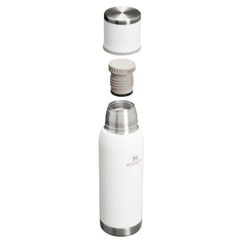 El Termo Stanley Adventure To-Go 750ml, en color blanco, se presenta con su tapa de dos piezas: una taza de acero inoxidable y blanca y un tapón de sellado gris que flota sobre la botella.