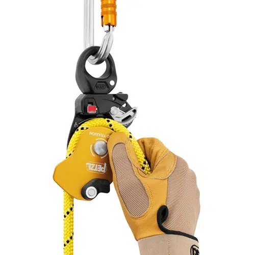 Una mano enguantada sostiene un descensor PETZL I'D S amarillo y negro conectado a una cuerda amarilla con marcas negras. El dispositivo, al igual que el robusto producto Petzl, como el Polea Industrial Petzl Pro Traxion, está conectado a un mosquetón metálico en una cuerda de escalada.