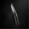 El cuchillo Opinel N°8 Mango de Ébano Ellipse, con una elegante hoja metálica y un mango de ébano Ellipse, se presenta sobre una superficie oscura y texturizada. La iluminación acentúa su nitidez y diseño.