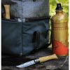 En un entorno de acampada, una mochila gris y verde presenta un hacha con mango de madera escondida en el bolsillo lateral, combinada con una botella de agua adornada en oro y rojo. Una navaja plegable Cuchillo Opinel N°8 Mango de Olivo colocada sobre una superficie oscura realza el ambiente rústico.