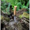 Un Cuchillo Opinel N°8 Mango de Roble descansa sobre un trozo de madera desgastada al aire libre, rodeado de un follaje verde vibrante y musgo. La hoja parcialmente visible realza el ambiente rústico y natural de la escena.