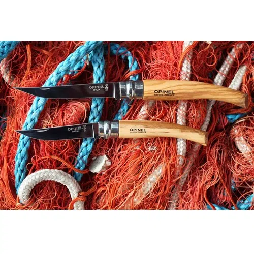 Dos cuchillos Opinel Slim Mango de Olivo se encuentran colocados sobre una maraña de cuerdas y redes de colores. Los cuchillos están abiertos, mostrando sus elegantes y pulidas hojas.