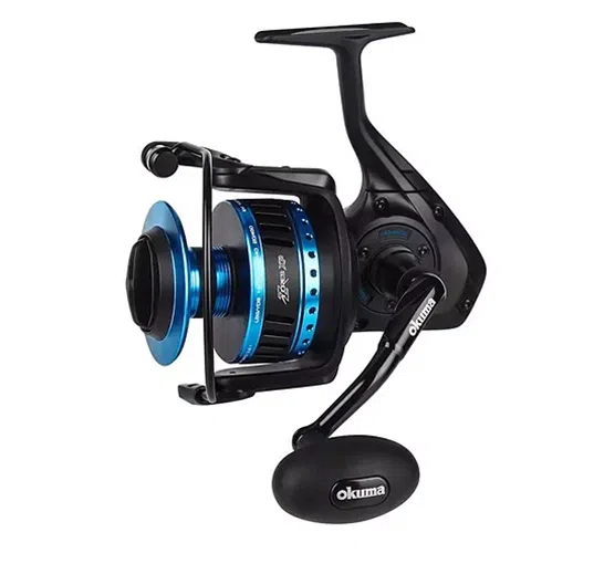 El carrete de pesca Carrete Azores ZXP 6000H Okuma de 220 m/0,35 mm presenta un elegante diseño en negro y azul con un mango grande con empuñadura negra y un carrete suave. El nombre de la marca, Okuma, se muestra de forma destacada tanto en el mango como en el carrete.