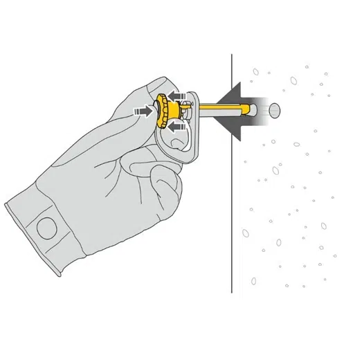 Una mano enguantada utiliza con destreza una herramienta amarilla y plateada para perforar con el anclaje amovible Petzl Coeur Pulse de 12 mm, guiada por una flecha para un anclaje preciso. Las partículas de polvo flotan cerca del orificio y capturan la acción detallada.