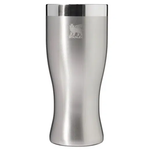 Frase reescrita: Un elegante vaso Stanley The Golden Hour Prismatic™ de 443 ml de acero inoxidable con un acabado pulido. La parte superior presenta una banda plateada reflectante y el logotipo de la marca "Stanley" grabado cerca del centro superior. Con su forma ligeramente similar a un reloj de arena, el vaso se ensancha en la parte superior e inferior.