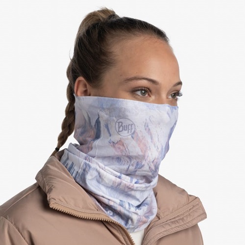 Una persona con cabello trenzado lleva una bandana Buff ThermoNet Blaise White sobre la parte inferior del rostro y una chaqueta marrón claro sobre un fondo blanco liso.