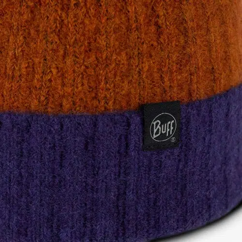 Primer plano de un gorro de mezclilla Buff Tricot Nilah con parte superior naranja y parte inferior violeta. Se ve una pequeña etiqueta negra que dice "Buff" en el borde.