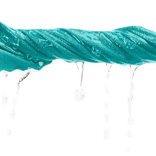Una toalla Airlite de Sea To Summit en color verde azulado retorcida con agua goteando sobre un fondo blanco.
