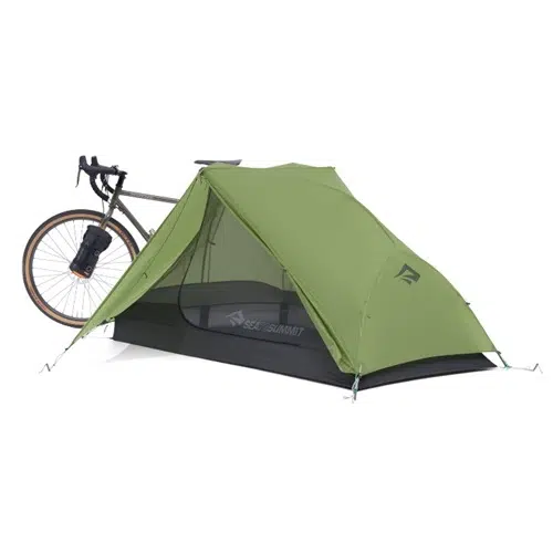 Una tienda de campaña verde Carpa Sea To Summit Alto TR2 Bikepack – 2 personas con paneles de malla está instalada junto a una bicicleta parcialmente visible, lo que sugiere una escena de campamento al aire libre.