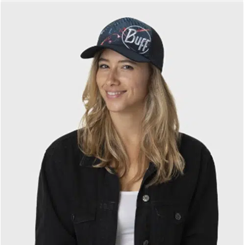 Una persona con el pelo largo sonríe mientras lleva puesta la Jockey Buff Trucker Xcross, una gorra de béisbol oscura con la palabra "Buff" en relieve. Irradia un estilo desenfadado con una chaqueta negra sobre una camiseta blanca, como si acabara de regresar de una aventura, sobre un fondo claro y sencillo.