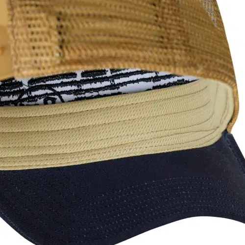 Una instantánea detallada del gorro Jockey Buff Trucker Tzom Stone Blue resalta su parte posterior de malla marrón y su ala curva de color azul piedra, con un forro interior que cuenta con un atrevido diseño gráfico en blanco y negro.