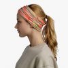 Una mujer de perfil con una cola de caballo lleva una diadema Bandana Buff Original EcoStretch Trem Citronella y un suéter beige, sobre un fondo blanco liso.
