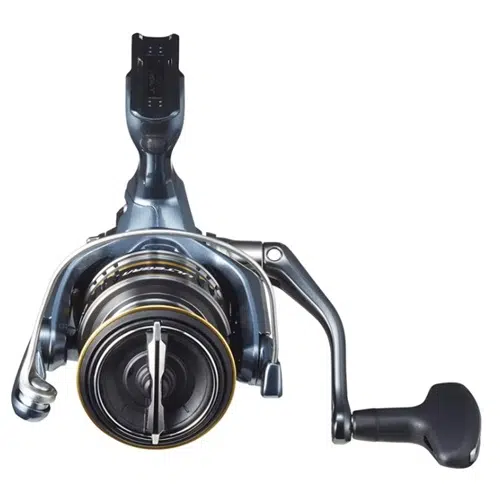 Una vista en primer plano de un carrete de pesca Shimano Ultegra FC muestra su cuerpo metálico con una manija en el lado derecho. El carrete cuenta con una bobina circular adornada con un elegante esquema de colores negro y plateado, realzado por un llamativo detalle amarillo alrededor del borde.