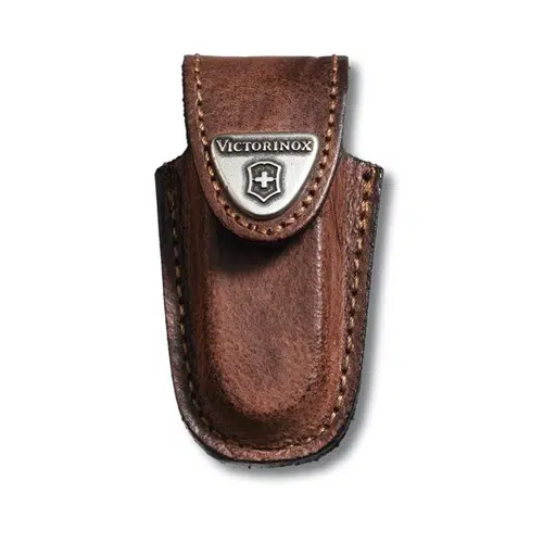 La Funda Victorinox Cuero Café 4.0531, una funda de cuero marrón para llevar una navaja de bolsillo, presenta un cierre de solapa asegurado con un emblema de metal que muestra el logotipo de la marca Victorinox y costuras reforzadas a lo largo de los bordes para mayor durabilidad.