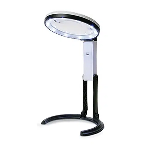 La Lupa Konus Flexo 120 12cm 1-5x es una lámpara de escritorio LED blanca con un cuello ajustable y un cabezal de luz circular. Cuenta con una bisagra flexible en el cuello para una fácil colocación y cuenta con una base curva y resistente para mayor estabilidad. El cabezal de luz tiene múltiples bombillas LED pequeñas distribuidas uniformemente alrededor de su borde.