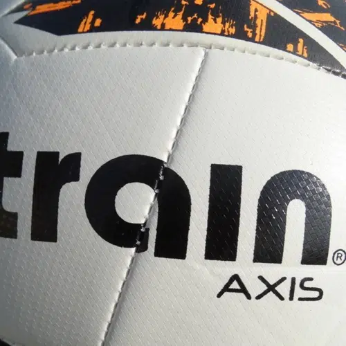 Primer plano del Balón Fútbol Train Axis N°5, que destaca su elegante diseño con paneles blancos y negros adornados con vibrantes detalles en naranja. El llamativo texto "train" y "AXIS" que se muestran de forma destacada en la superficie llama la atención.