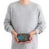 Una persona con una sudadera gris sostiene un paquete compacto con forma de capullo con la etiqueta "Liner Sea To Summit Coolmax Breeze", diseñado para ofrecer la máxima comodidad y transpirabilidad. Está de pie sobre un fondo blanco liso que enfatiza el diseño elegante del paquete.