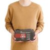 Una persona que lleva un suéter color canela sostiene un paquete de Liner Sea To Summit Reactor Fleece Mummy Standard sobre un fondo blanco. El paquete oscuro tiene una etiqueta roja que destaca la idoneidad de este forro para mejorar la calidez y la comodidad en cualquier configuración de saco de dormir.