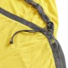 Primer plano de una tela amarilla y gris con cordón y etiqueta, probablemente parte de una prenda de Sea To Summit para actividades al aire libre. Equipada con un botón para ajustar el ajuste, se parece al forro de la serie Liner Sea To Summit Reactor Mummy Standard para bolsos tipo momia.