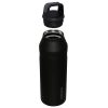 Sobre ella se encuentra una Botella Térmica Stanley Cap and Carry de 1,4 L en color negro, con tapa de rosca y asa para transportarla fácilmente, lo que la hace perfecta para hidratarse mientras se está de viaje.