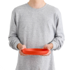 Una persona que viste una sudadera gris sostiene con ambas manos un recipiente de plástico rojo vacío que se parece al plato Sea to Summit Passage de 1020 ml, sobre un fondo blanco liso.