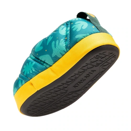 Presentamos las Pantuflas Térmicas Atakama Outdoor Futaleufú Kids Nu-B Foam, unas zapatillas alegres que presentan un diseño de hojas tropicales azules y verdes en la parte superior de la tela, resaltado por una banda amarilla alrededor de la base. Las suelas negras vienen equipadas con agarres texturizados y muestran la marca Futaleufú Kids, ofreciendo una comodidad divertida para los jóvenes aventureros.