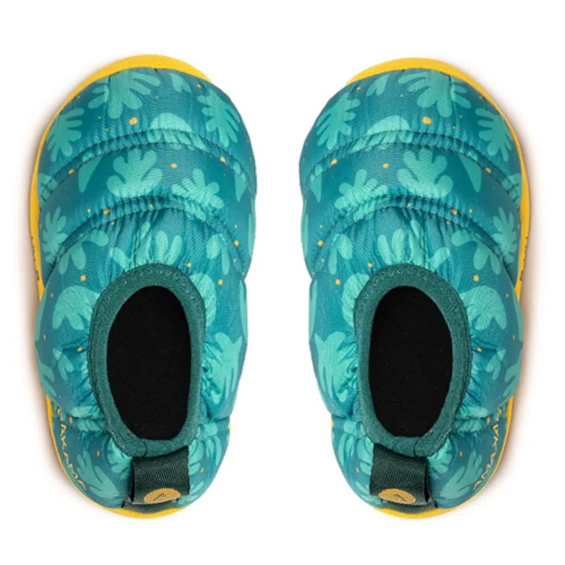 Vista superior de las zapatillas sin cordones Pantuflas Térmicas Atakama Outdoor Futaleufú Kids Nu-B Foam que presentan una textura acolchada y un patrón de hojas verdes y amarillas sobre un fondo azul. Estas zapatillas cuentan con una suela amarilla y tiradores traseros elásticos para facilitar su uso.