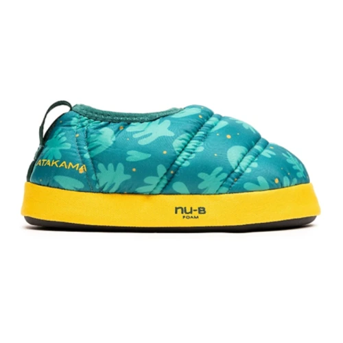 Un zapato sin cordones solitario, vibrante, de color verde azulado con detalles en amarillo en la suela. El zapato presenta un patrón de formas similares a hojas y el nombre de la marca "ATAKAMA" se muestra de manera destacada en el costado. Siguiendo el modelo de Pantuflas Térmicas, la suela presenta la etiqueta "NU-B FOAM" y es parte de la línea Pantuflas Térmicas Atakama Outdoor Futaleufú Kids.