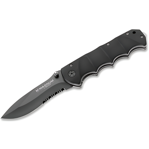 Navaja Boker Magnum Black Spear 01RY247, de color negro, con hoja parcialmente dentada. El mango ergonómico tiene ranuras para los dedos y una pequeña anilla de metal en el extremo. La hoja muestra el logotipo "Magnum by Böker" y cuenta con un botón para el pulgar para facilitar su apertura.