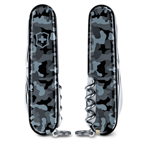 Dos navajas Cortapluma Victorinox Huntsman 1.3713.942 presentan elegantes patrones de camuflaje en negro y gris. Una navaja se muestra de lado, mientras que la otra se muestra de frente, destacando un práctico sacacorchos. Cada navaja incluye un pequeño lazo en su base, lo que realza su diseño versátil.