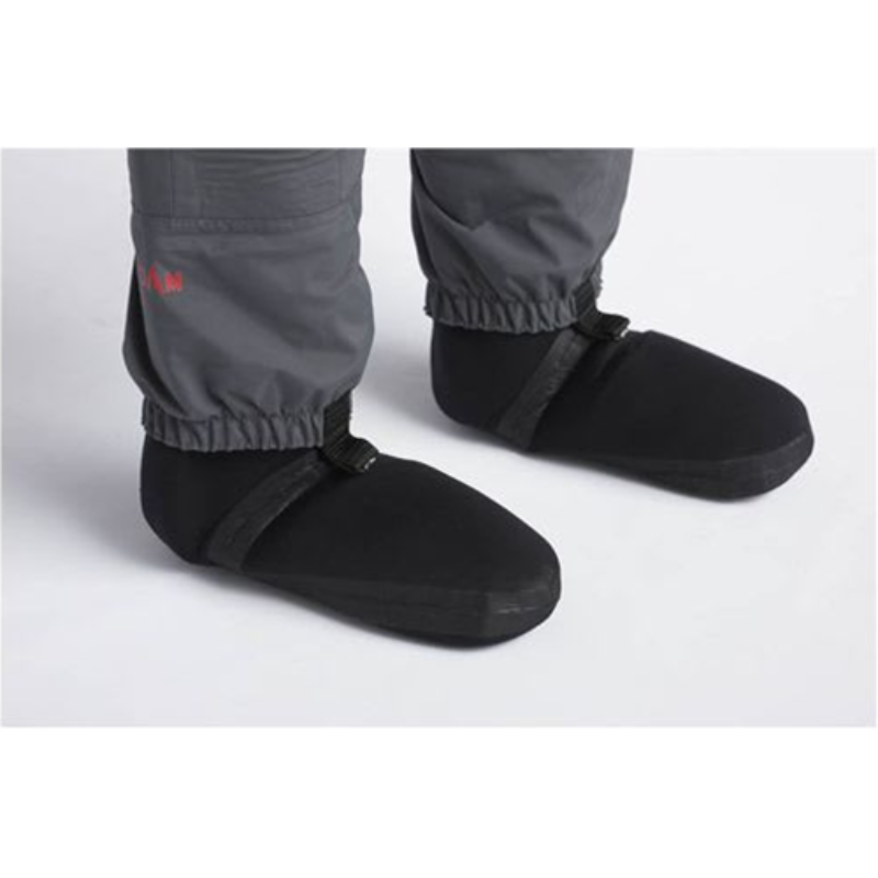 Una persona lleva un par de botines Wader Respirable Dam Stockingfoot en color negro, junto con pantalones grises con puños elásticos. Estos botines incluyen correas ajustables en la parte superior y están diseñados por expertos para mantener el calor en condiciones de frío.