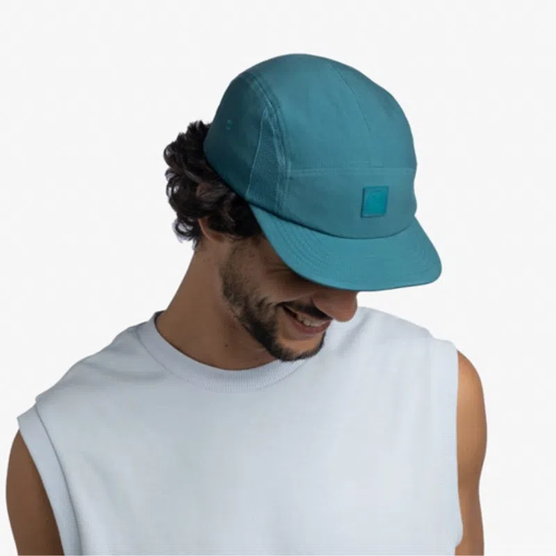 Hombre usando el Jockey Buff 5 Panel Go en color teal, mostrando un diseño moderno y deportivo.