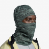 La persona, que luce el Pasamontañas Buff DryFlx Pro Solid Jade en un diseño verde texturizado que cubre la mayor parte de su rostro y cabeza, también está vestida con una chaqueta beige y negra sobre una parte superior gris claro, todo sobre un fondo blanco liso.