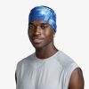 Una persona sonríe a la cámara mientras usa una diadema Cinta Buff CoolNet UV Wide Attel Blue y una camisa sin mangas gris claro, sobre un fondo blanco liso.