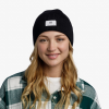 Una persona con cabello largo y rubio sonríe mientras usa un gorro Buff Tricot Drisk negro y una camisa a cuadros verde sobre una parte superior blanca.