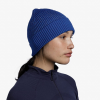 Perfil de una persona que viste un gorro Buff Merino Active Solid Cobalt combinado con una chaqueta oscura con cremallera, sobre un fondo blanco liso.