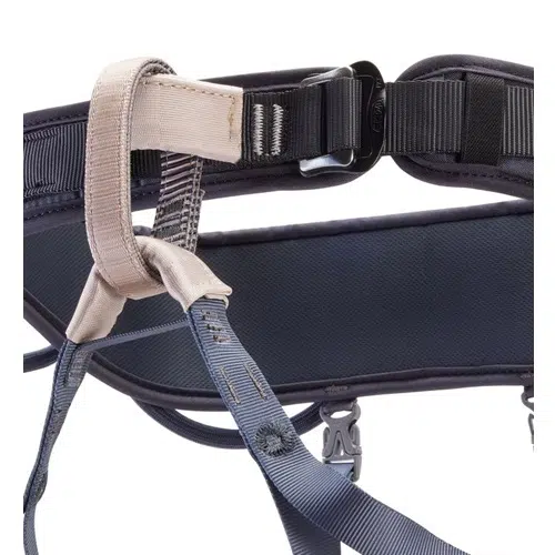 Primer plano de un arnés de escalada Arnés Petzl Corax LT de color oscuro con detalles en beige. Este arnés cuenta con correas ajustables, una hebilla resistente y presillas de metal para sujetar el equipo de escalada. Está fabricado con materiales duraderos y bien cosido para garantizar la seguridad durante las actividades de escalada.