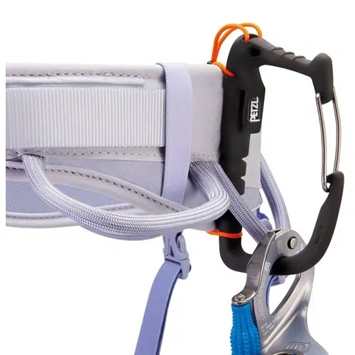 Primer plano del arnés Corax LT Women de Arnés Petzl en color gris claro. Tiene un mosquetón negro enganchado y una correa elástica naranja. Debajo del arnés cuelga un dispositivo de seguridad azul.