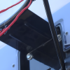 Primer plano del cuadro de una bicicleta en el que se destacan los cables de cambio rojos y los componentes metálicos, que evocan la precisión de las luminarias Aro Básquetbol Uk Time Sport con Pedestal Profesional S021F. El cuadro oscuro, con tornillos visibles y un mecanismo de cambio, destaca sobre un fondo bellamente desenfocado.