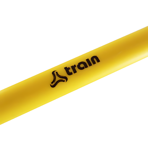 Primer plano de un objeto cilíndrico amarillo, probablemente la pulsera de fitness Micro Valla Train, con la palabra "train" y un logotipo estilizado impreso en negro, que mide 6 pulgadas.