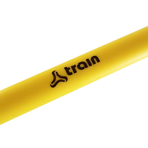Primer plano de un objeto cilíndrico amarillo, probablemente la pulsera de fitness Micro Valla Train, con la palabra "train" y un logotipo estilizado impreso en negro, que mide 6 pulgadas.