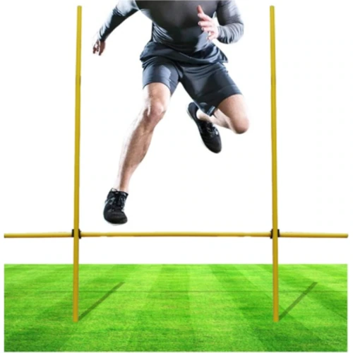 En pleno salto sobre una valla amarilla en un campo de césped, se muestra la parte inferior del cuerpo de alguien vistiendo el Kit de Entrenamiento Outdoor Train, lo que resalta su intenso esfuerzo de entrenamiento.