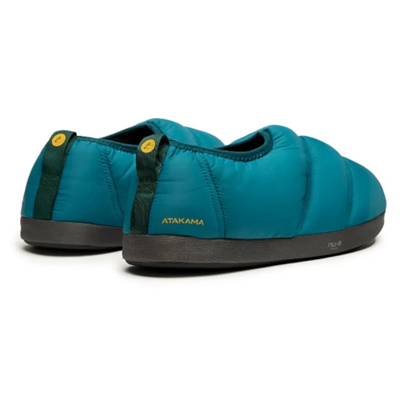 Pantuflas Térmicas Atakama Outdoor Futaleufú Nu-B Foam en color verde azulado con suela negra sobre fondo blanco. Estas pantuflas presentan un diseño acolchado y el logo de la marca se puede ver en el talón, lo que resalta su estilo outdoor.