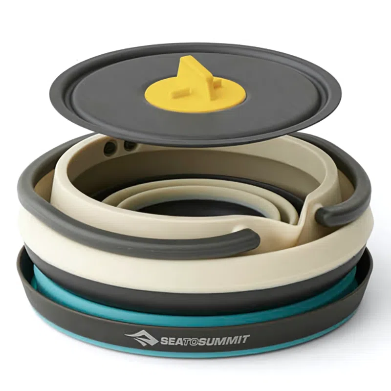 El juego de cocina de 3 piezas Sea To Summit Frontier incluye una olla plegable para acampar con tapa que cuenta con un asa amarilla y está diseñada con capas en gris, beige y azul. Presenta de manera destacada el logotipo de "Sea to Summit", perfecto para uso individual.