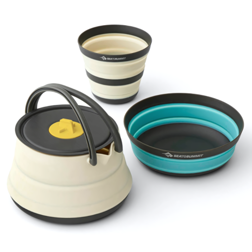 Un juego de cocina plegable diseñado para una persona que incluye una tetera blanca con asa negra y tapa amarilla, una taza plegable blanca y negra y un recipiente plegable azul y negro. El juego de cocina de 3 piezas Sea To Summit Frontier garantiza comodidad en tus aventuras al aire libre.