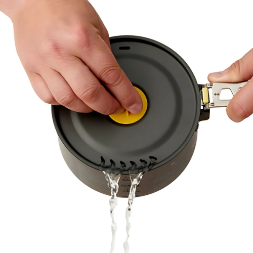 Se muestran manos que demuestran la función de vertido de la olla Olla Sea To Summit Ultralight Frontier, que incluye un asa amarilla en la tapa para permitir que el agua salga a través de los picos incorporados. Esta olla tiene un asa de metal adherida a un costado.