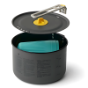 Una olla para acampar gris con la tapa abierta, parte del Set de Cocina 3pc Sea To Summit Frontier 2L, muestra un asa de metal plegable. En el interior, se ve una taza plegable de color verde azulado. El exterior está adornado con marcas de medición e instrucciones en texto pequeño.