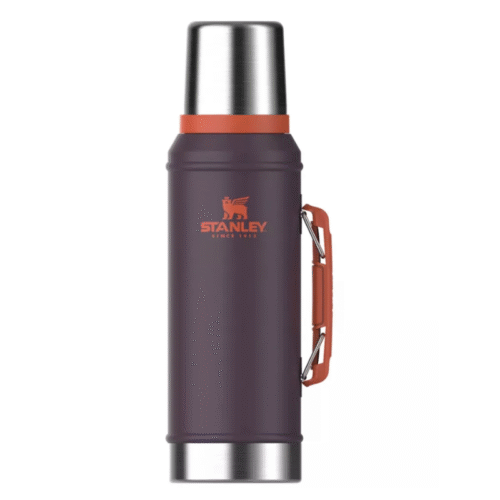 Un termo Stanley Classic Termo Stanley de color morado oscuro, de 950 ml, con tapa plateada, logotipo naranja y asa naranja en el lateral, sobre un fondo blanco liso.
